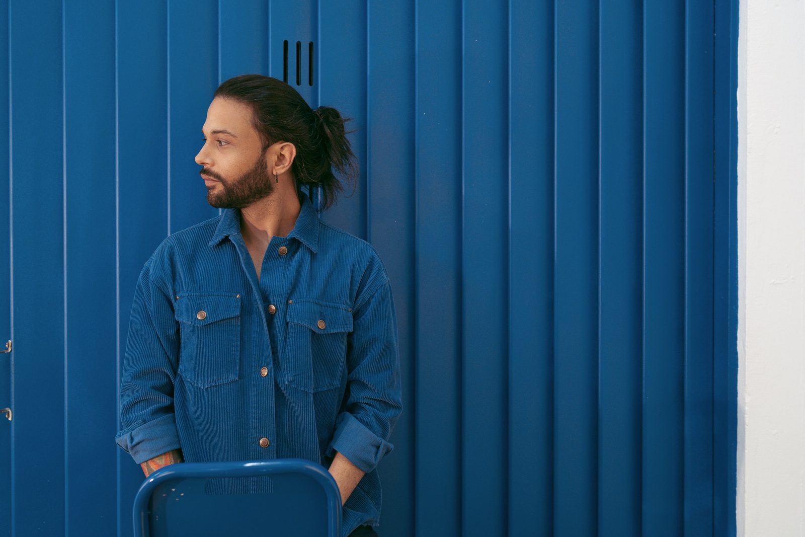 Pazz mirando de perfil frente a una pared azul